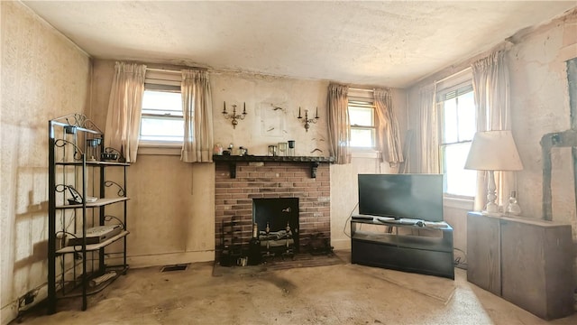 interior space with a textured ceiling, a fireplace, concrete flooring, and a healthy amount of sunlight