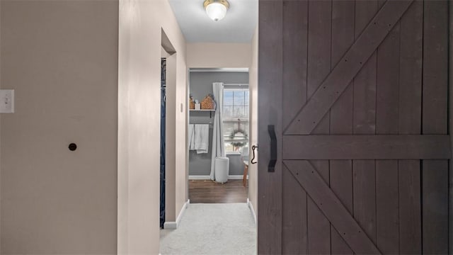 hallway with a barn door and light carpet