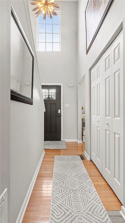 entryway featuring an inviting chandelier, hardwood / wood-style flooring, and a high ceiling