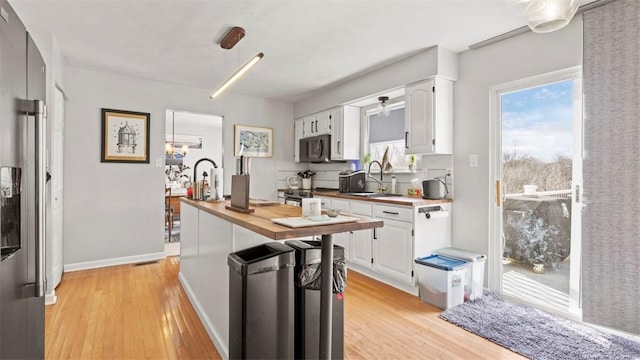 kitchen featuring dishwasher, white cabinetry, sink, and wooden counters