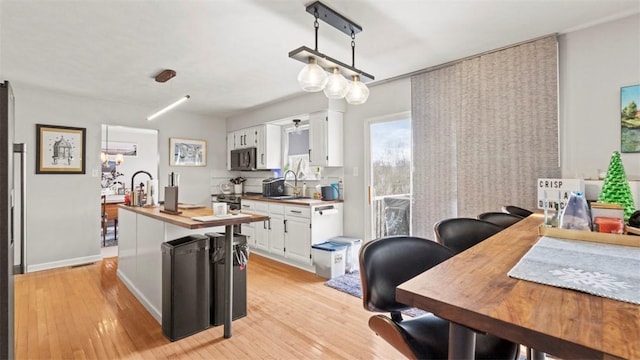 kitchen with white cabinetry, sink, light hardwood / wood-style floors, and butcher block countertops