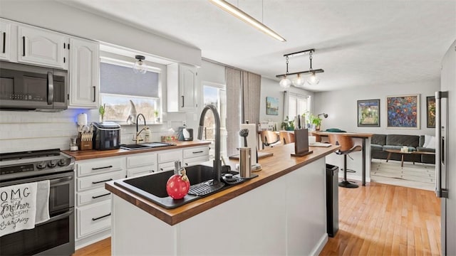 kitchen featuring sink, wooden counters, white cabinetry, stainless steel appliances, and decorative backsplash