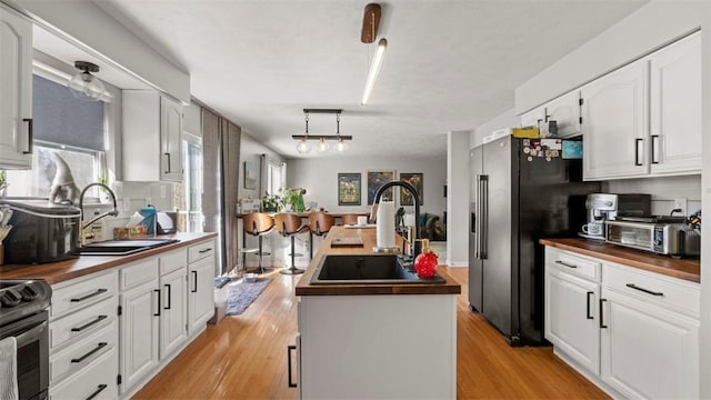 kitchen with sink, wood counters, and stainless steel fridge with ice dispenser