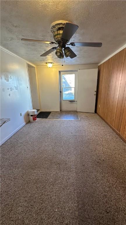 spare room featuring ceiling fan, a textured ceiling, carpet, and wood walls