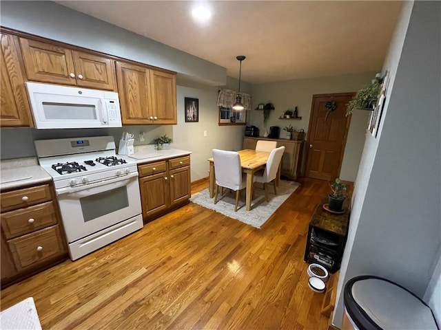 kitchen with hardwood / wood-style flooring, white appliances, and hanging light fixtures