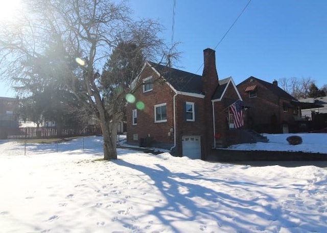 snow covered rear of property featuring a garage