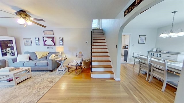 living room featuring wood-type flooring and ceiling fan with notable chandelier