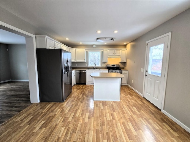 kitchen with white cabinetry, appliances with stainless steel finishes, a kitchen island, and light hardwood / wood-style flooring