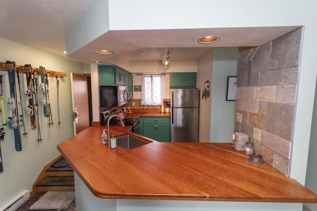 kitchen featuring appliances with stainless steel finishes, backsplash, green cabinetry, a baseboard radiator, and kitchen peninsula