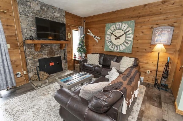 living room featuring a stone fireplace and wood walls