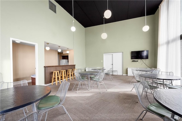 carpeted dining room featuring a towering ceiling