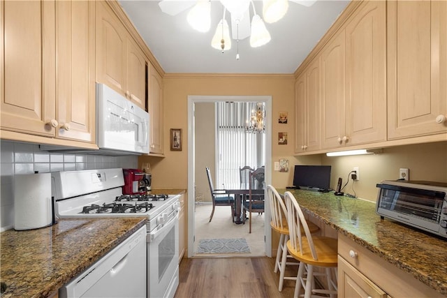 kitchen featuring light hardwood / wood-style floors, built in desk, white appliances, and dark stone counters