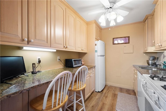 kitchen with light brown cabinetry, sink, white appliances, built in desk, and ceiling fan