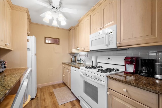 kitchen featuring sink, white appliances, dark stone countertops, backsplash, and light brown cabinets