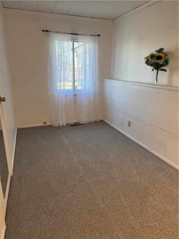 spare room featuring a paneled ceiling and dark carpet