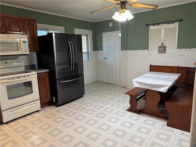 kitchen with white appliances, dark brown cabinets, tile walls, ornamental molding, and ceiling fan