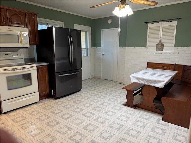 kitchen featuring dark brown cabinetry, crown molding, tile walls, ceiling fan, and white appliances