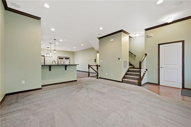 unfurnished living room featuring sink, crown molding, and light colored carpet