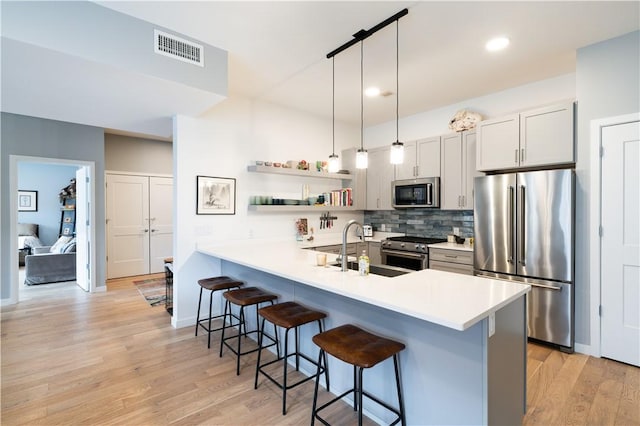 kitchen with appliances with stainless steel finishes, pendant lighting, sink, a breakfast bar area, and kitchen peninsula