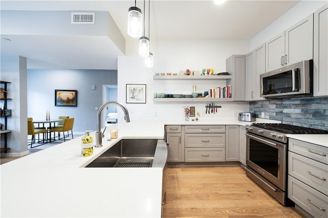 kitchen with sink, light hardwood / wood-style flooring, gray cabinets, appliances with stainless steel finishes, and hanging light fixtures