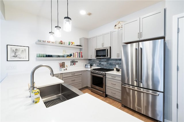 kitchen featuring hanging light fixtures, gray cabinets, stainless steel appliances, and sink