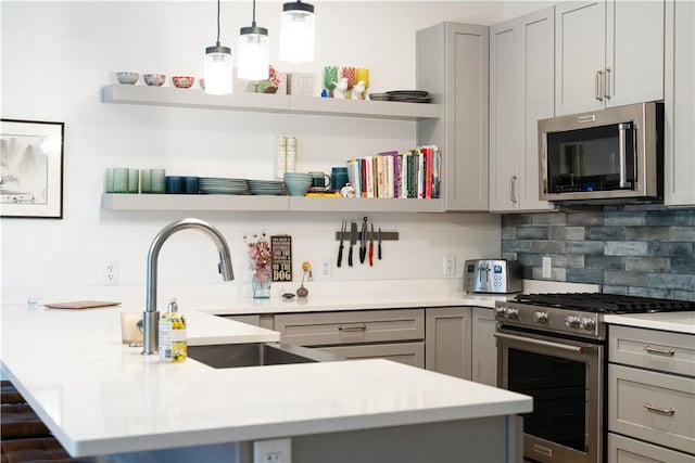 kitchen with sink, tasteful backsplash, decorative light fixtures, gray cabinets, and stainless steel appliances