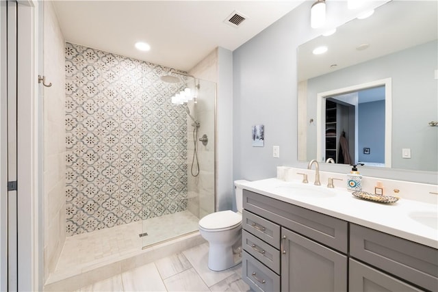 bathroom with vanity, toilet, and a tile shower