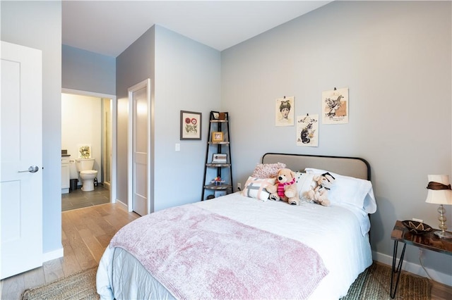 bedroom with ensuite bath and light hardwood / wood-style floors