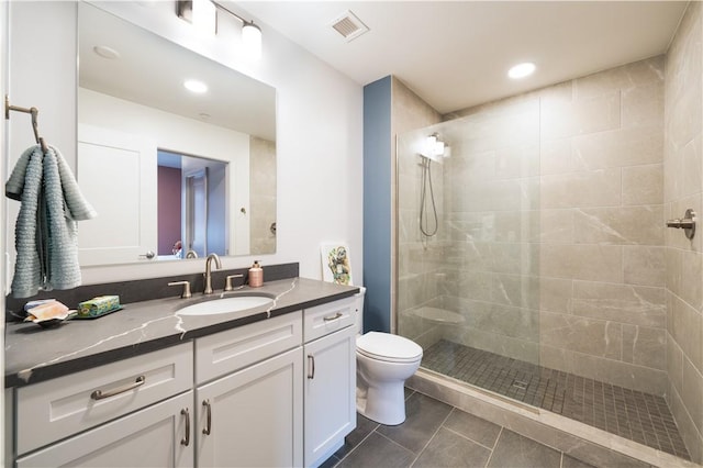 bathroom featuring vanity, tiled shower, tile patterned floors, and toilet