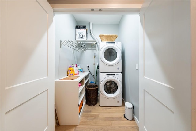 clothes washing area with stacked washing maching and dryer and light wood-type flooring