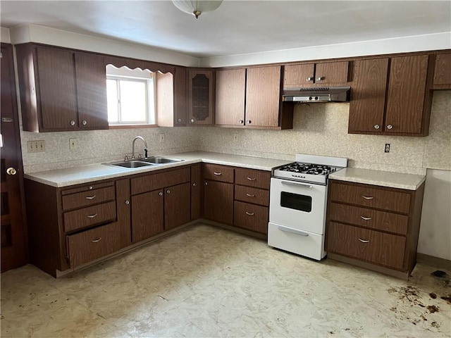 kitchen with tasteful backsplash, dark brown cabinetry, sink, and white gas range oven