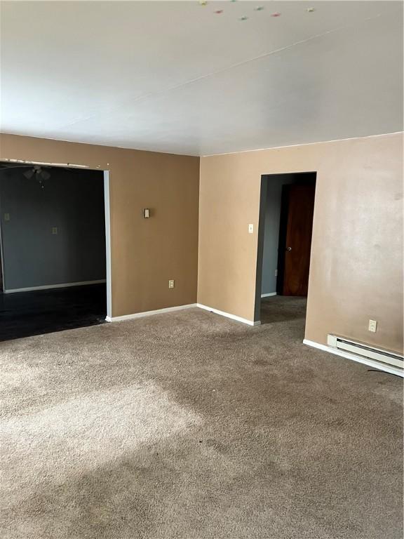 carpeted empty room featuring baseboard heating