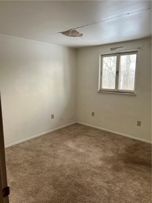 carpeted spare room featuring baseboards