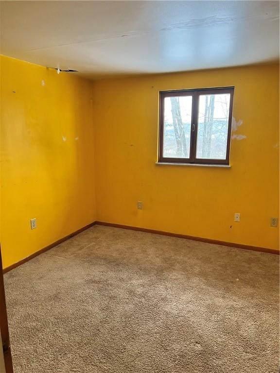 carpeted spare room featuring baseboards