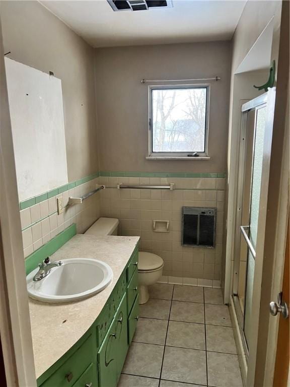 bathroom featuring heating unit, tile walls, vanity, toilet, and tile patterned floors