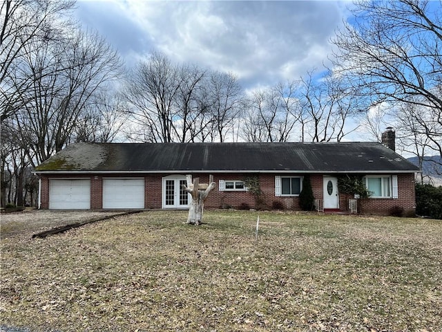 ranch-style house with french doors, brick siding, a chimney, an attached garage, and a front yard