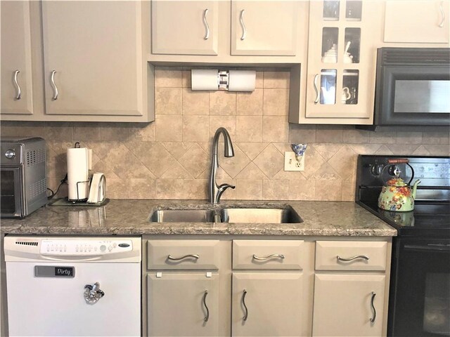 kitchen featuring tasteful backsplash, sink, black appliances, and dark stone counters