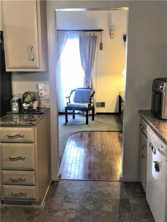 kitchen featuring dark stone counters and white dishwasher