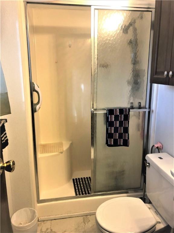 bathroom with toilet and a shower with shower door