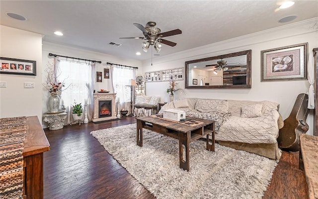 living room featuring dark wood-type flooring, ornamental molding, and ceiling fan