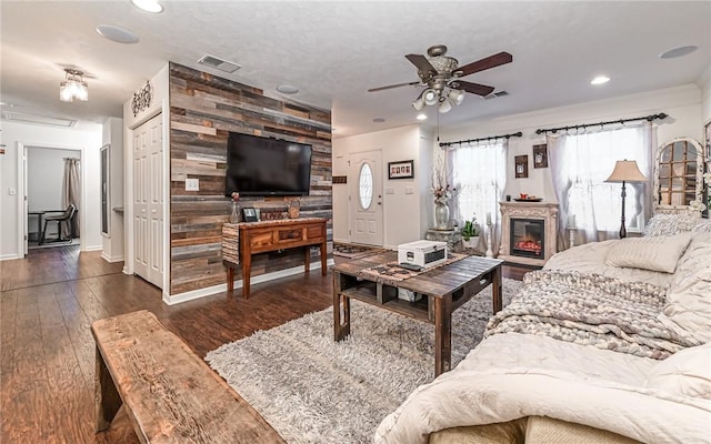 living room with dark hardwood / wood-style flooring, ceiling fan, and wooden walls