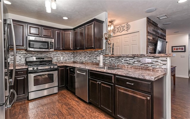 kitchen with sink, tasteful backsplash, dark hardwood / wood-style floors, kitchen peninsula, and stainless steel appliances