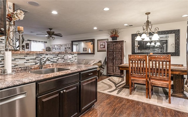 kitchen featuring tasteful backsplash, dishwasher, sink, hanging light fixtures, and dark wood-type flooring