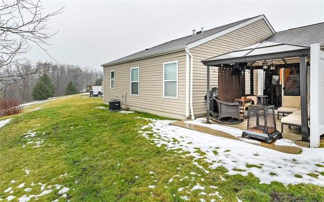 snow covered rear of property with central AC, a patio area, a gazebo, an outdoor fire pit, and a yard