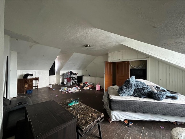 bedroom with wood-type flooring, vaulted ceiling, and a textured ceiling