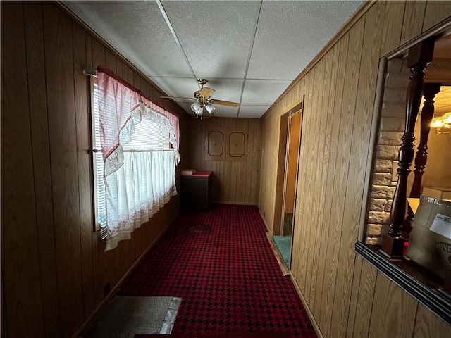 corridor featuring carpet flooring, a textured ceiling, and wood walls