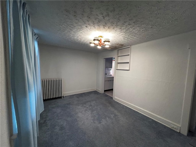 carpeted empty room featuring radiator, a notable chandelier, and a textured ceiling