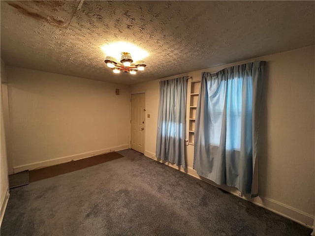 carpeted empty room with a textured ceiling and a notable chandelier