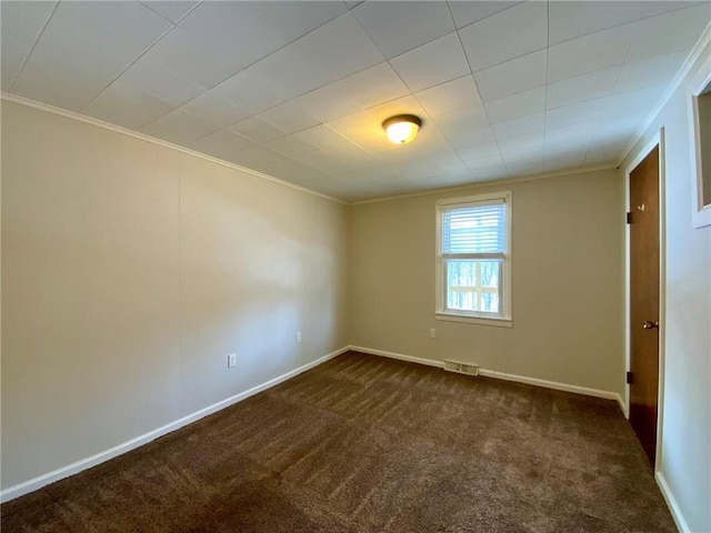 empty room with ornamental molding and dark colored carpet