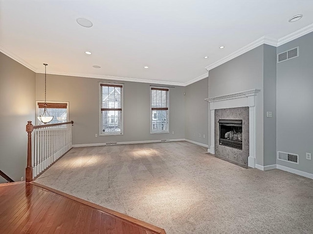 unfurnished living room with ornamental molding, a tiled fireplace, and hardwood / wood-style floors